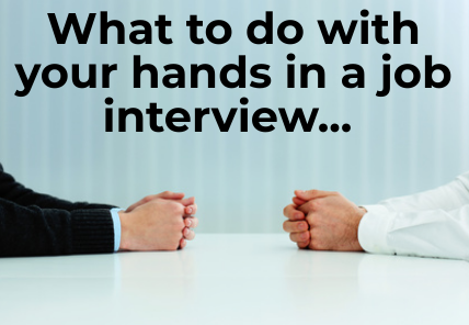Hands clasped loosely together on desk with words "What to do with your hands in a job interview..."